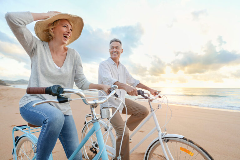retired couple biking by beach